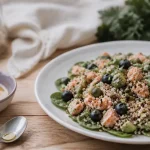 Aliment riche en nutriment : salade quinoa-saumon, avocat et myrtilles sur table en bois